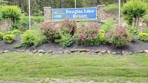 Douglas Lake Resort -lomakeskukseen johtava opaste, jonka ympärillä on maisemoituja puutarhoja ja kivimuuri.
