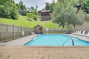 Ein Schwimmbecken mit Holzterrasse, Liegestühlen und einem kleinen haushaltsähnlichen Gebäude im Hintergrund.