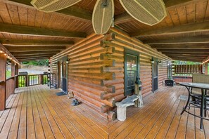 Eine Blockhütte mit einer Holzterrasse, einer Veranda und einer Steinsitzbank.