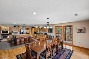 A spacious kitchen with wooden cabinets, a central island, and a dining area with a large wooden table and chairs. - 6‑Bedroom Mountain Escape with Forested Views (Sevierville)