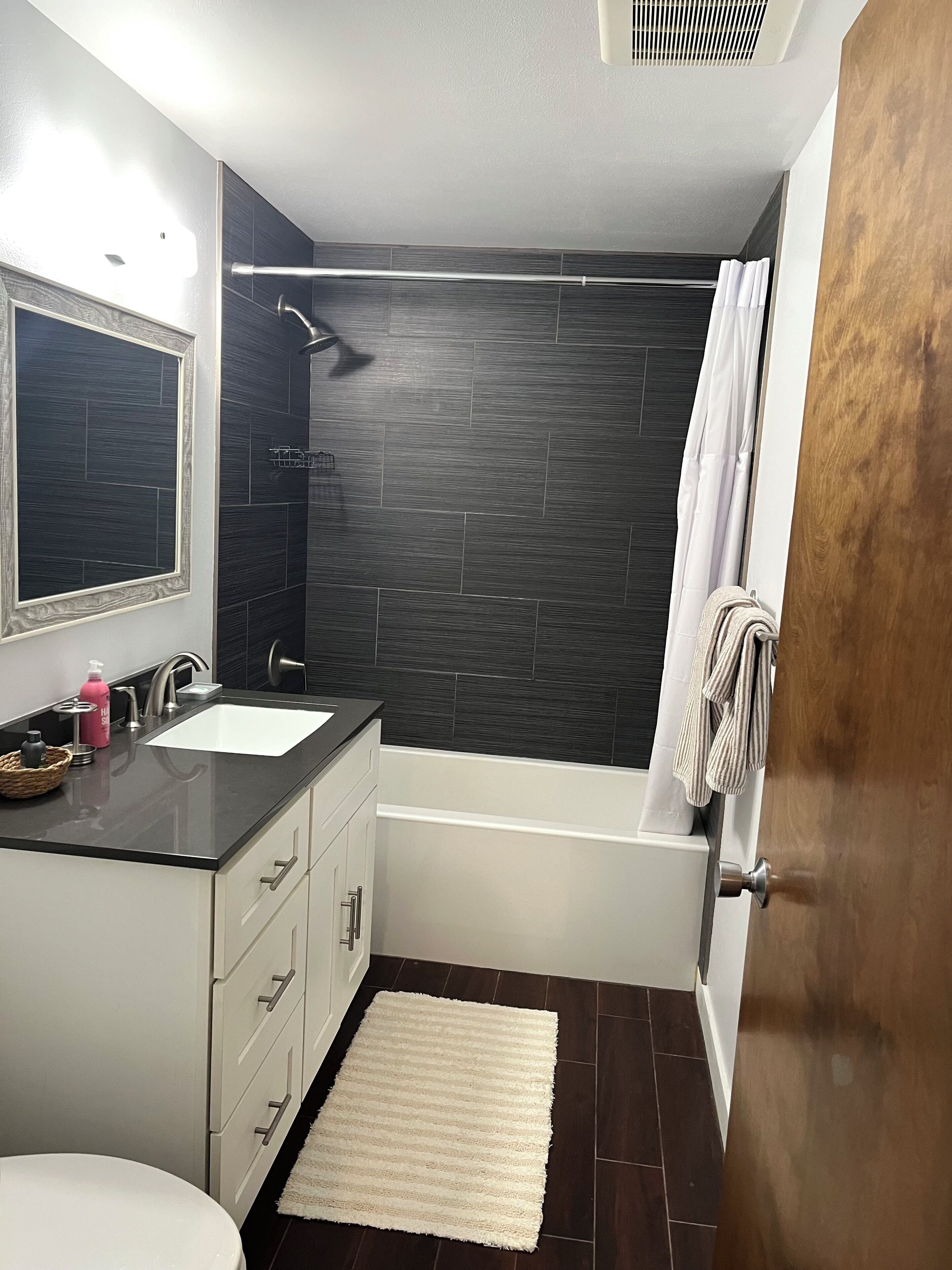 A modern bathroom with a bathtub, a shower, a sink with a mirror, and a toilet.