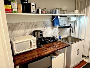Une cuisine compacte équipée d’un four à micro-ondes, d’une machine à café et d’un petit réfrigérateur.