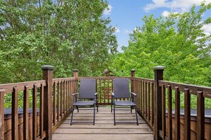 Une terrasse en bois avec deux chaises et une rambarde en bois.