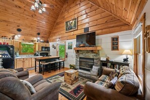Ein Innenraum einer Blockhütte mit Kamin, Holzmöbeln und einer Küchenzeile.