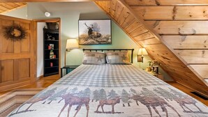 A bedroom with a checkered bedspread, a mounted deer picture, and a wooden ceiling. - Serene Cozy Cabin w/ Hot Tub & Games (Sevierville)