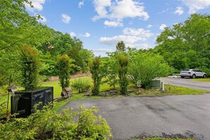 A parking area with a paved surface, surrounded by greenery and trees. - Serene Cozy Cabin w/ Hot Tub & Games (Sevierville)