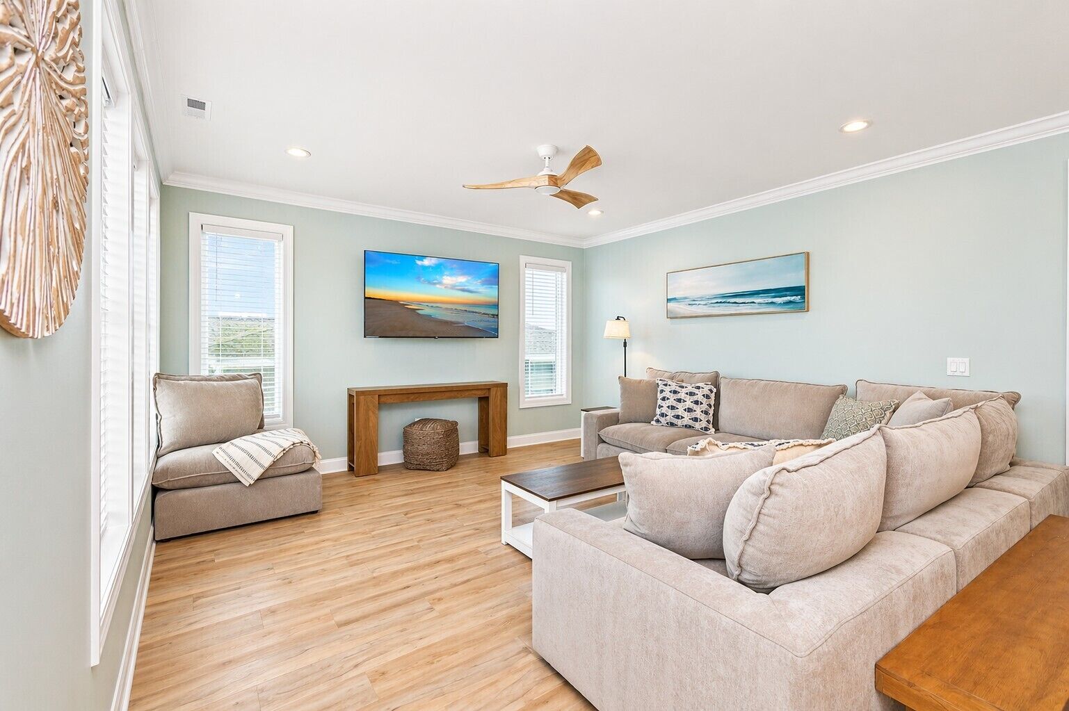 A living room with a sofa, a coffee table, a fireplace, and a ceiling fan.