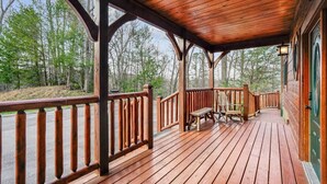 Um deck de madeira com guarda-corpos, um banco e uma mesa.