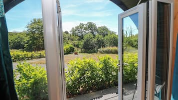 Blick durch eine Glastür auf eine Holterrasse mit einem Garten im Hintergrund.