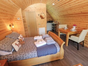 A cozy wooden cabin room with a bed, a small table, and a chair.