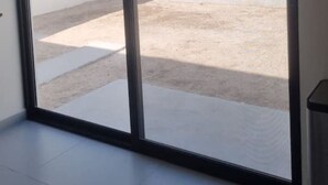 A room with a large sliding glass door leading to an outdoor area with a concrete floor and a white wall. - 3 Bedroom home in Gated Community (La Paz)