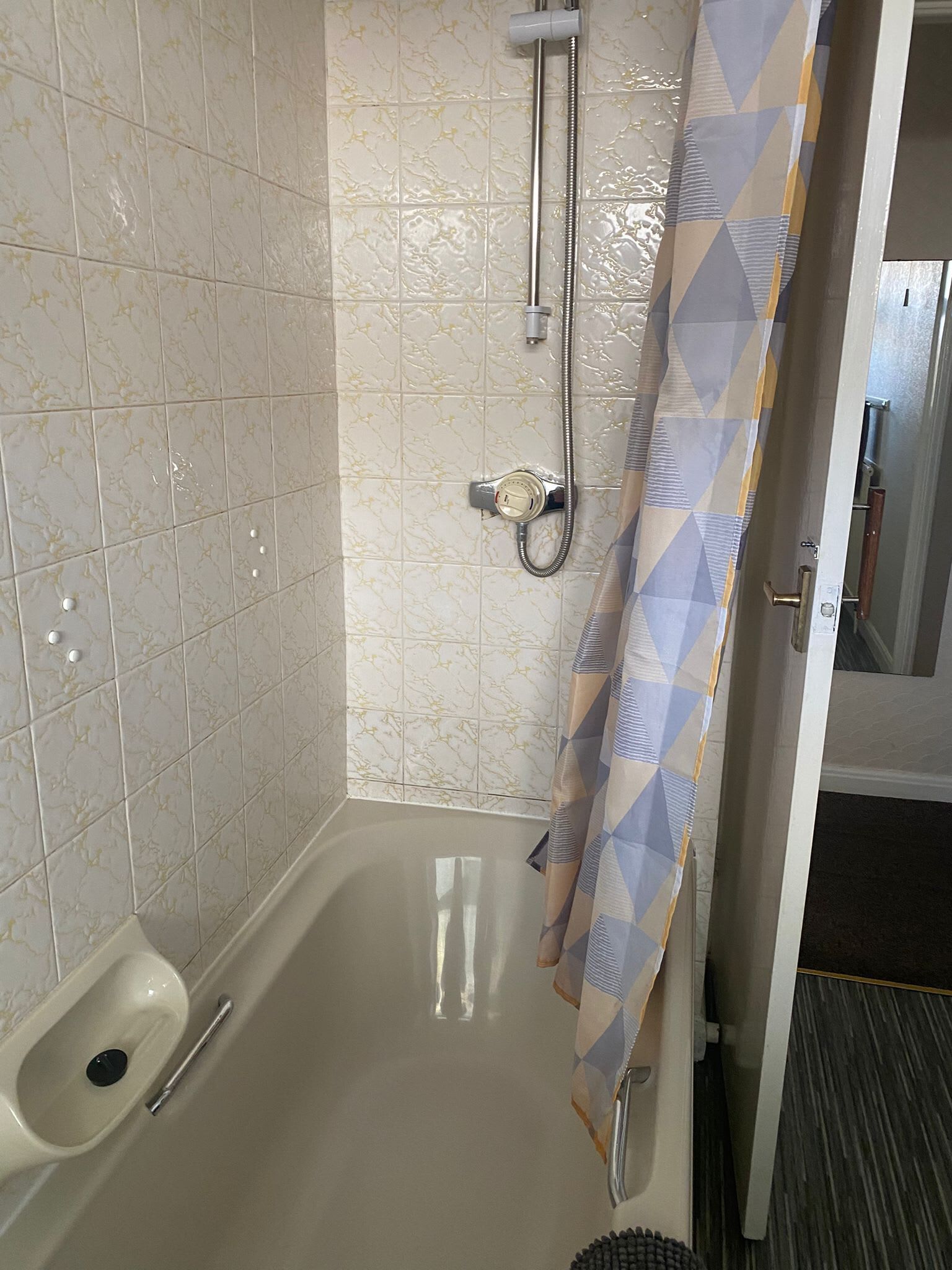 A bathroom with a shower, toilet, and a towel rack.