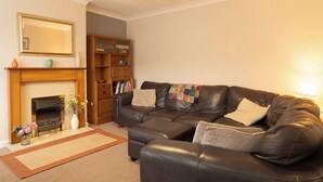 A living room with a leather sofa, a fireplace, a bookshelf, and a mirror on the wall. - No 48 - 3 Bedroom Heworth in York (York)