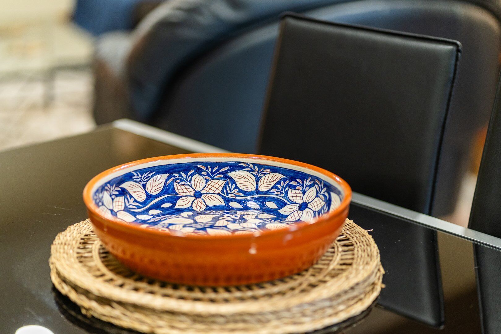 Eine Schüssel mit blau-orangenem Muster auf einer gewebten Matte auf einem Tisch.