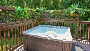 A hot tub on a wooden deck with a lattice fence and greenery in the background. - 4BR Home | Theater + Hot tub + Games + Fire Pit (Gatlinburg)