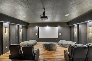 A home theater room with a large screen, comfortable seating, and a projector. - 4BR Home | Theater + Hot tub + Games + Fire Pit (Gatlinburg)