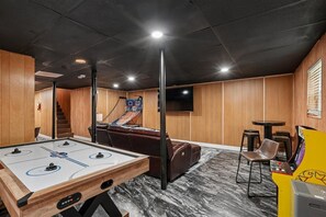 A room with a foosball table, a sofa, a TV, and a pool table. - 4BR Home | Theater + Hot tub + Games + Fire Pit (Gatlinburg)