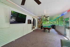 A pool room with a pool table, ceiling fan, and large windows. - 4BR Home | Theater + Hot tub + Games + Fire Pit (Gatlinburg)