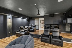 A room with multiple massage chairs, a wooden floor, and a ceiling projector. - 4BR Home | Theater + Hot tub + Games + Fire Pit (Gatlinburg)