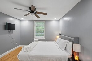 A bedroom with a bed, a ceiling fan, a TV mounted on the wall, and a window with blinds. - 4BR Home | Theater + Hot tub + Games + Fire Pit (Gatlinburg)