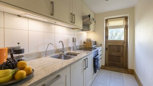 Una cocina moderna con dos fregaderos, un microondas y una puerta de madera.