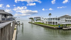 A waterfront property with a dock, a covered walkway, and a row of houses with balconies. - Cheerful Canal Home with Gorgeous Views (Galveston)