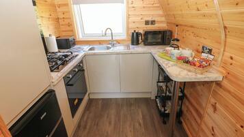 A compact kitchen with a sink, stove, microwave, and a window above the sink.