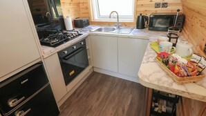 Une cuisine compacte équipée d’une cuisinière à gaz, d’un four, d’un évier et d’une fenêtre située au-dessus de l’évier.
