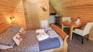 A cozy wooden cabin room with a bed, a small table, and a chair.