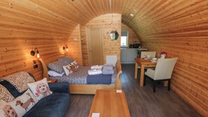 Un intérieur chaleureux, avec des éléments en bois, comprenant un lit, un canapé et un coin repas.