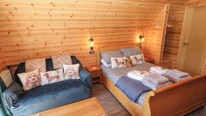 Une pièce chaleureuse, aménagée dans un chalet en bois, avec un lit, un canapé et une petite table.