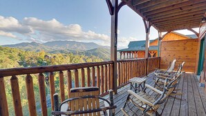 Una terrazza in legno con sedie a dondolo che si affaccia su un paesaggio montuoso.