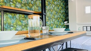 Ett modernt hotellrum med ett matbord i trä, dukat för två personer, en glaskaraff och en skål på bordet.