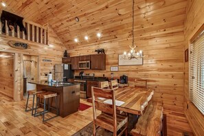 A wooden cabin interior with a kitchen, dining area, and a loft bedroom. - Inviting 2- Bedroom Cabin w/ Hot Tub (Gatlinburg)