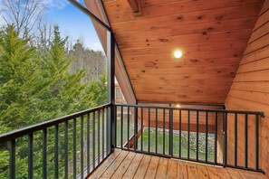 A wooden balcony with a black railing, overlooking a forested area. - Inviting 2- Bedroom Cabin w/ Hot Tub (Gatlinburg)