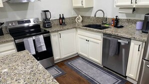 A kitchen with white cabinets, a stainless steel oven, a sink, and a dishwasher.
