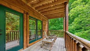 Une terrasse en bois, agrémentée de chaises et d’une table, entourée d’un feuillage verdoyant.