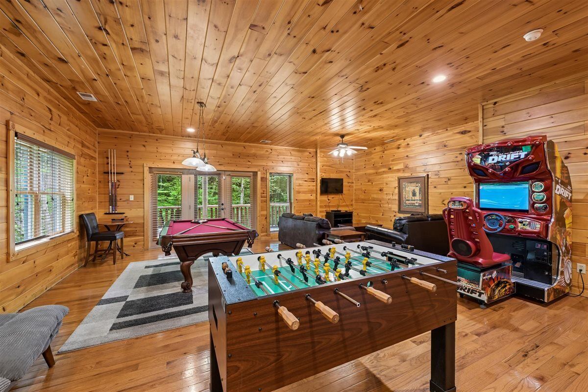 Un interior de madera con mesa de futbolín, mesa de billar y máquina de videojuegos.
