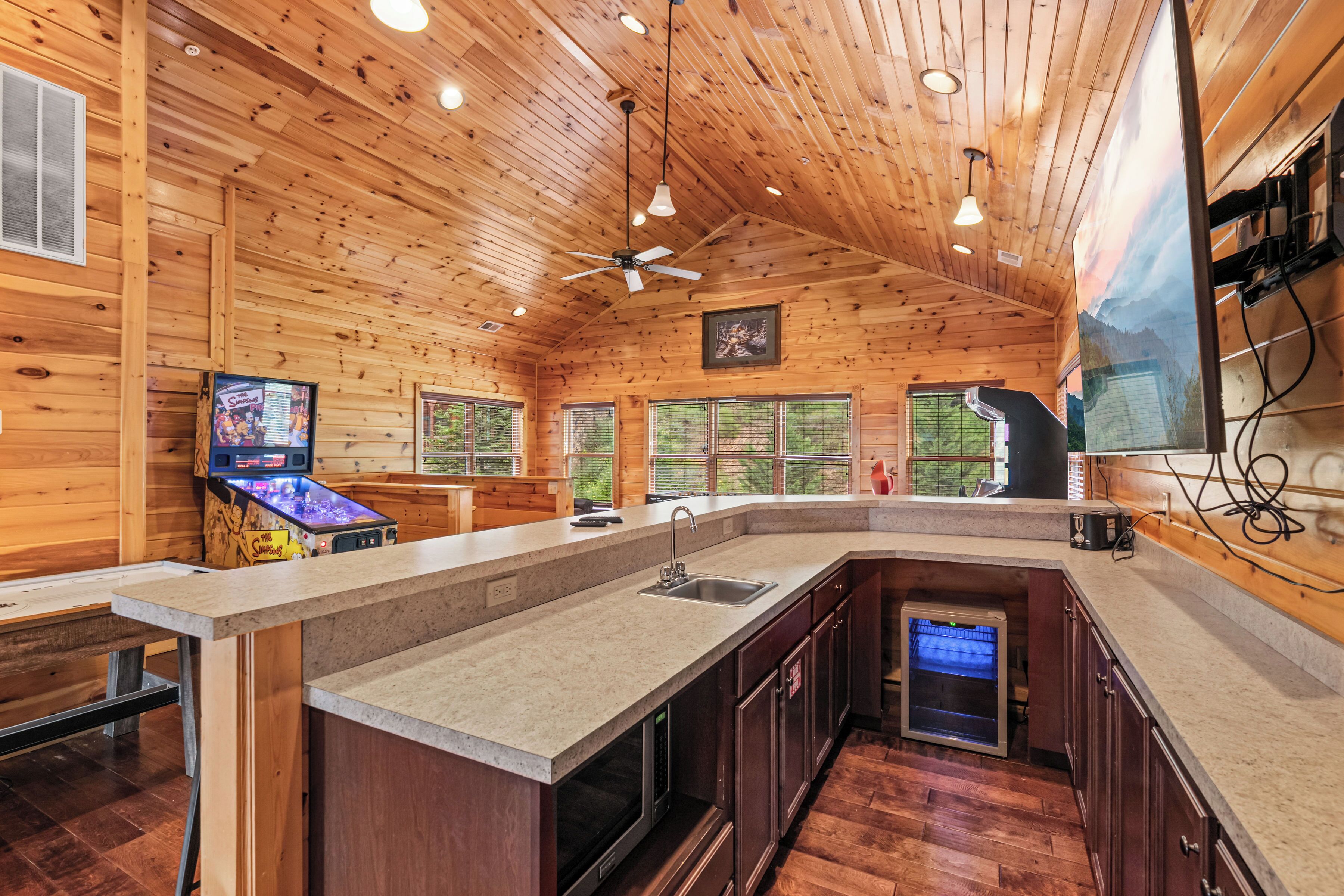 Une cuisine avec des murs en bois, un grand îlot central doté d’un évier et un ventilateur de plafond.