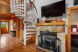 A wooden interior with a spiral staircase, a fireplace, a flat-screen TV, and a sign indicating Wi-Fi availability. - Luxury Mountain Retreat w/ Hot Tub & Views (Pigeon Forge)