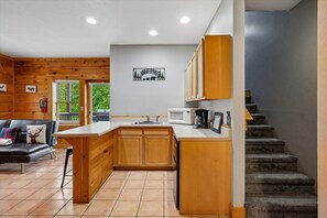 A compact kitchen with wooden cabinets, a white countertop, and a built-in microwave. - Luxury Mountain Retreat w/ Hot Tub & Views (Pigeon Forge)