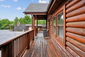 A log cabin with a wooden deck, a covered porch, and a chimney. - Luxury Mountain Retreat w/ Hot Tub & Views (Pigeon Forge)