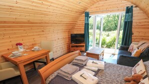 Une pièce confortable avec un lit, une table ornée d’un vase et de verres, un téléviseur et un canapé avec des coussins.