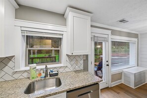 A kitchen with a granite countertop, stainless steel sink, and white cabinetry. - Family Comforts Await w/ Games & Hot Tub (Pigeon Forge)