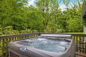 A hot tub on a wooden deck surrounded by lush greenery.