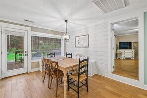 A dining area with a wooden table and chairs, a chandelier, and a view through a door to a living room. - Family Comforts Await w/ Games & Hot Tub (Pigeon Forge)