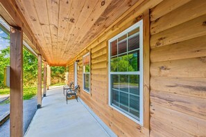A wooden exterior with large windows and a covered porch area. - Cozy Cabin w/ Fire Pit & Hot Tub (Pigeon Forge)