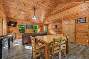 A log cabin interior with a dining area, kitchen, and seating space. - Cozy Cabin w/ Fire Pit & Hot Tub (Pigeon Forge)