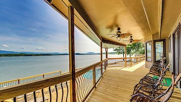A covered outdoor deck with wooden flooring, metal railings, and wicker chairs.