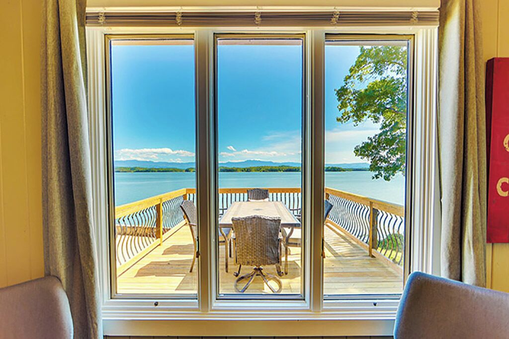 A room with a large window overlooking a deck with a table and chairs.